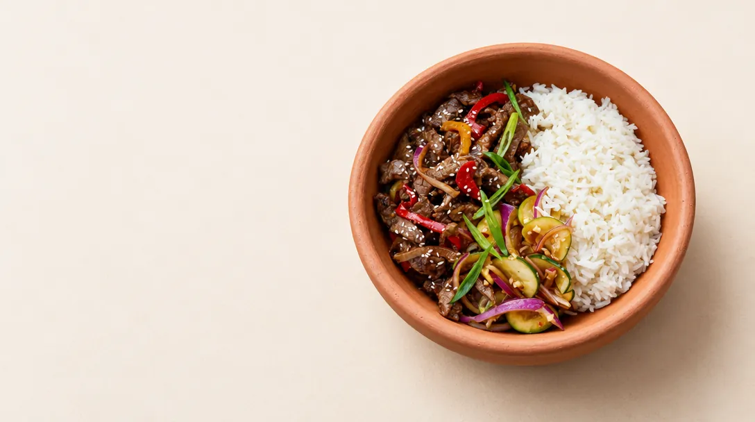 Clay bowl of stir-fried beef with peppers, courgette and white rice